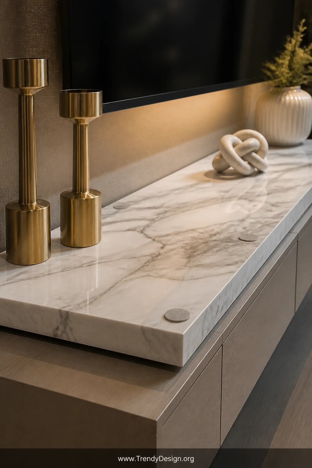 A closeup detail shot of a thick white marble slab with natural grey veining sitting beneath a flatscreen TV on a media conso