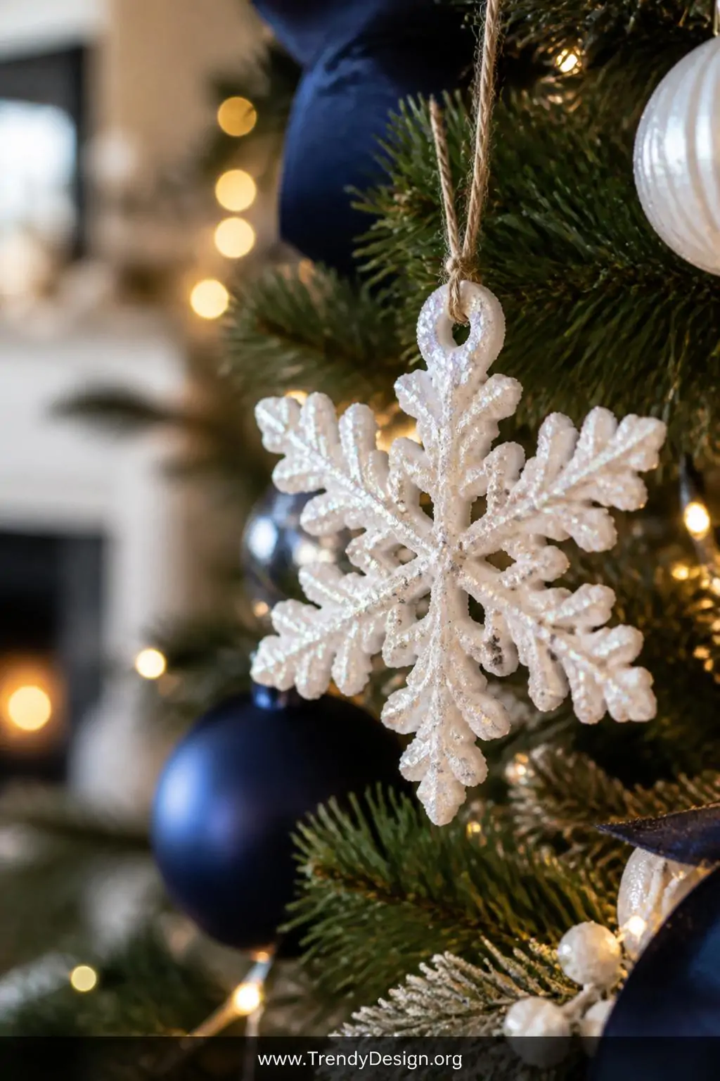 White iridescent salt dough snowflake ornament dusted with glitter hanging on a decorated Christmas tree, navy blue and white holiday styling, soft bokeh background with warm fairy lights, closeup shot