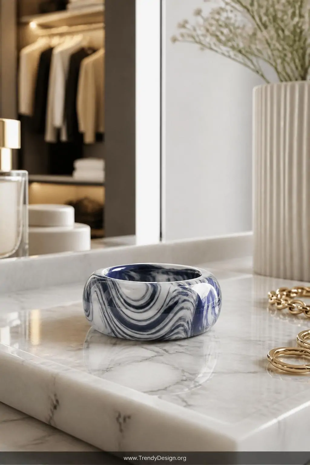 Marbled swirl polymer clay ring in white and navy blue with glossy varnish finish displayed on a white marble vanity tray, boutique dressing room, luxe minimalist style, closeup shot with soft diffused natural light catching the fluid swirl patterns