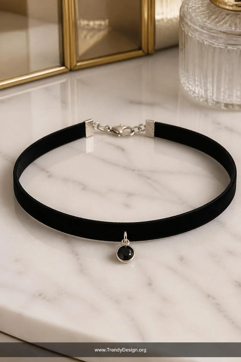 Black velvet ribbon choker with lobster clasp and small pendant on a white marble vanity surface, soft warm studio lighting, closeup shot showing deep matte texture and silver hardware against pale stone