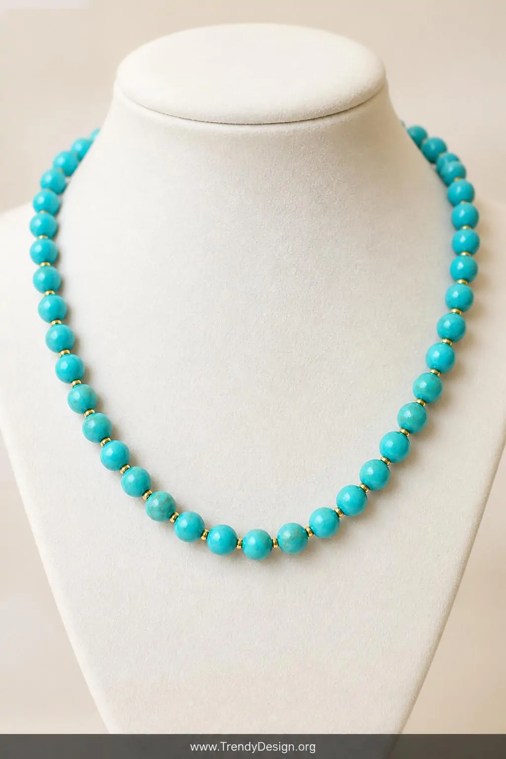 Single-strand turquoise bead necklace with sterling silver lobster clasp and small gold spacer beads displayed on a white velvet jewelry bust, soft studio lighting, closeup shot capturing the uniform 8mm round beads and polished collarbone-length arrangement against a clean cream background.