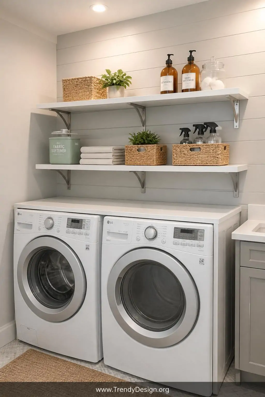 Wide shot of a compact laundry room with crisp white floating shelves installed at two staggered heights above a front-loadin