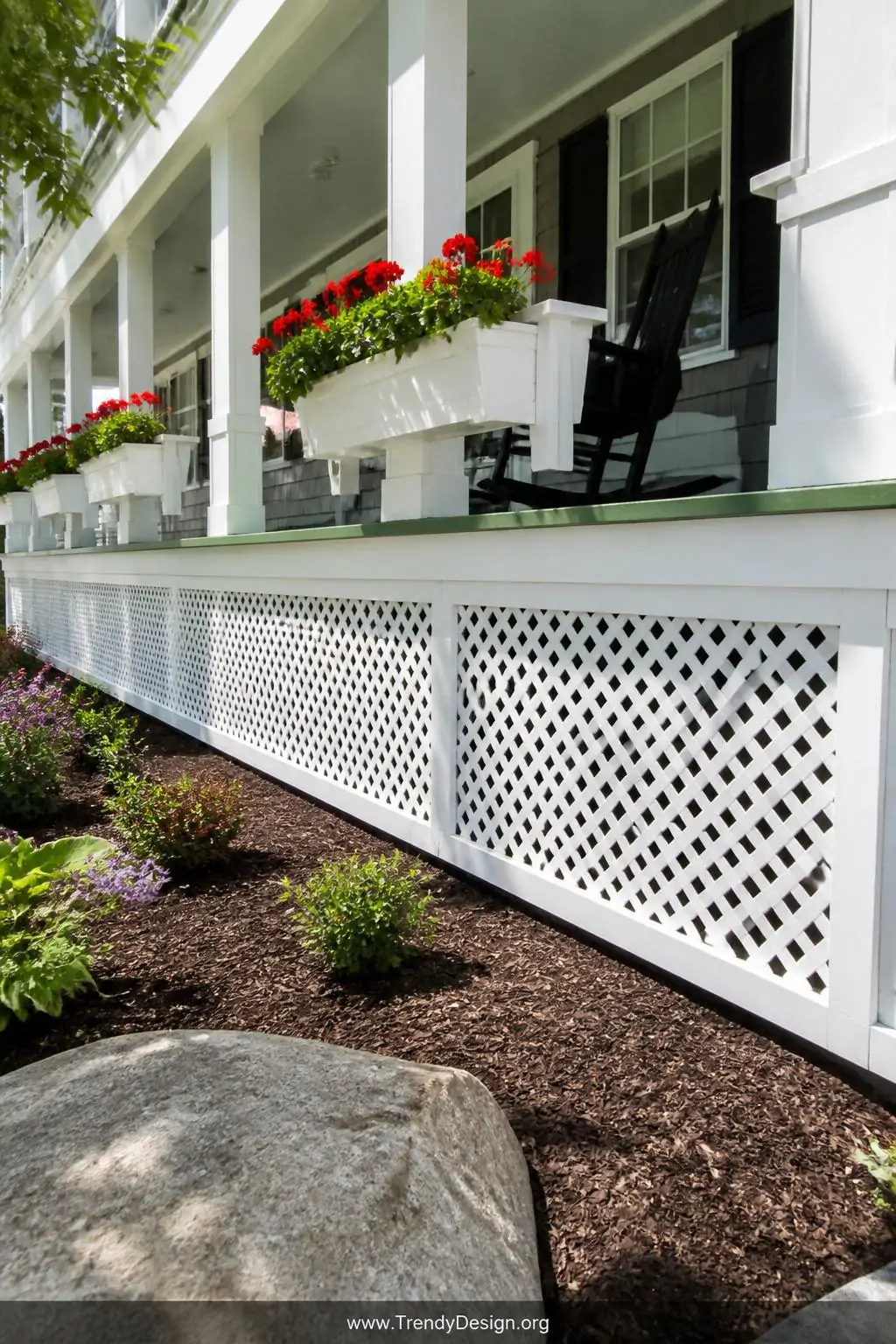 Wide-angle photorealistic shot of a pristine white vinyl lattice porch skirting wrapping a charming cottage exterior, bright 
