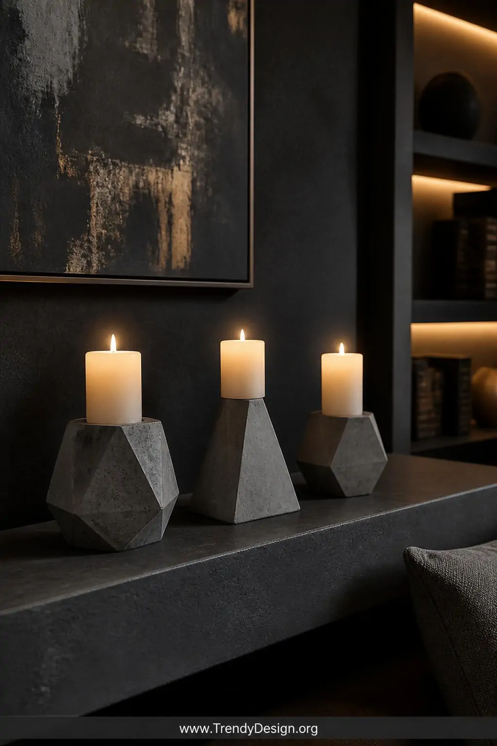 A medium shot of three angular hexagonal and pyramid-shaped concrete candle holders arranged on a dark charcoal concrete shel