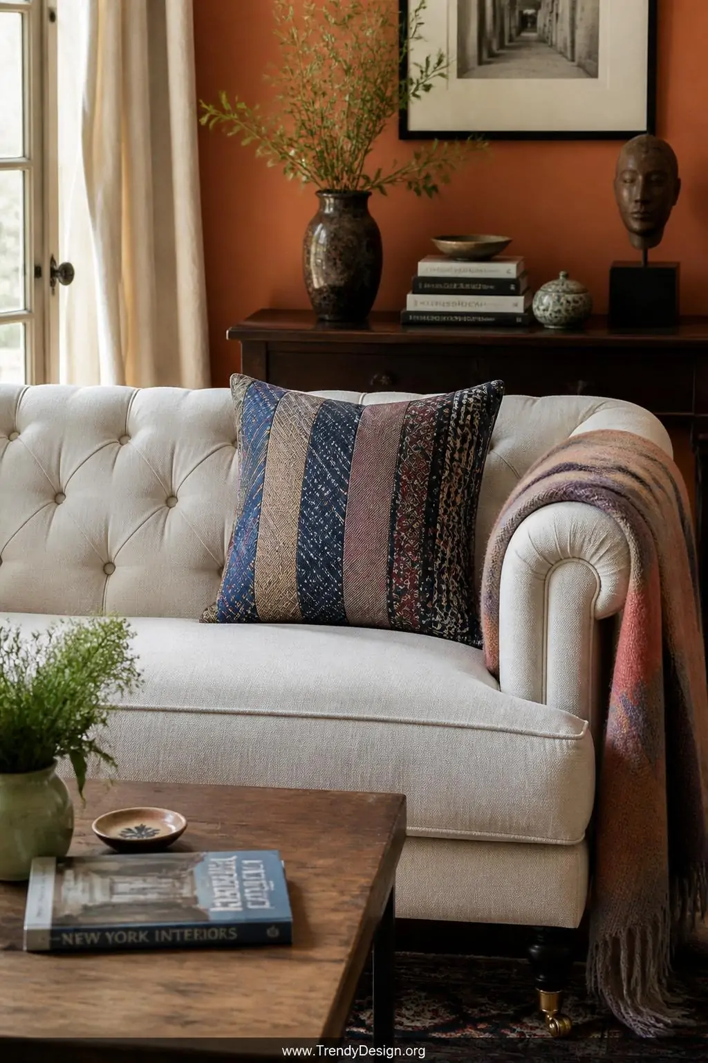 Patchwork necktie pillow cover in stripes, paisleys, and solids arranged on a tufted linen sofa, soft afternoon window light, medium shot of an eclectic living room with warm terracotta walls and a wool throw draped over the armrest.