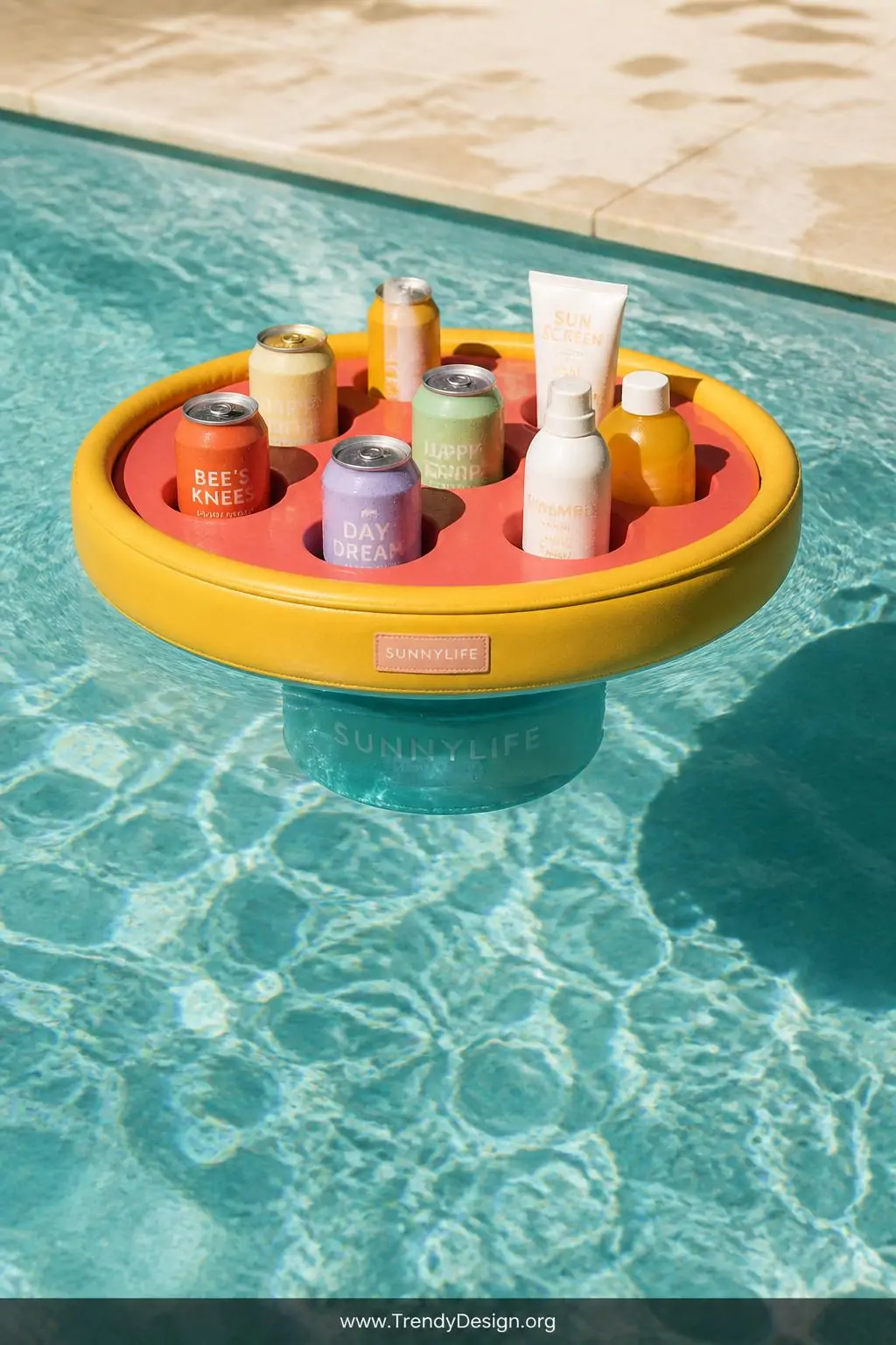 Floating drink holder tray with colorful canned beverages and sunscreen bottles drifting on bright aqua pool water, outdoor pool surface, playful summer style, coral and yellow accents on the insulated tray, weighted base visible beneath crystal-clear water, soft afternoon light dancing across rippling surface, medium closeup shot