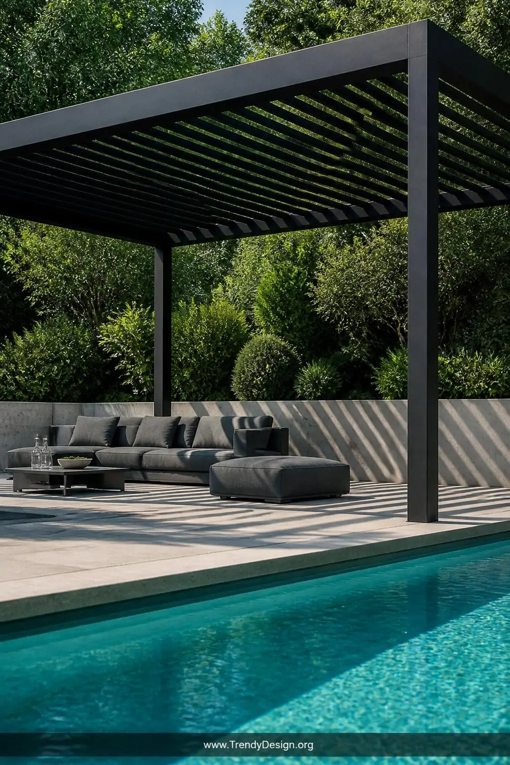 Black powder-coated steel pergola with sleek horizontal slats casting dramatic shadow stripes across a minimalist concrete pool deck, charcoal frame contrasting sharply against turquoise water and dense emerald landscaping, low-profile gray modular lounge furniture below, medium shot from poolside angle.