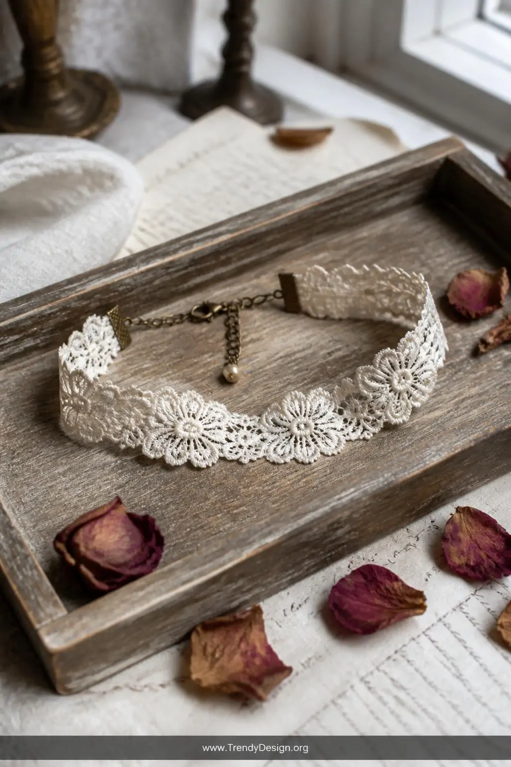 Ivory lace trim choker with delicate floral pattern on a weathered wooden jewelry tray beside dried rose petals, diffused natural window light, medium shot capturing vintage romantic texture and antique tea-stained edges