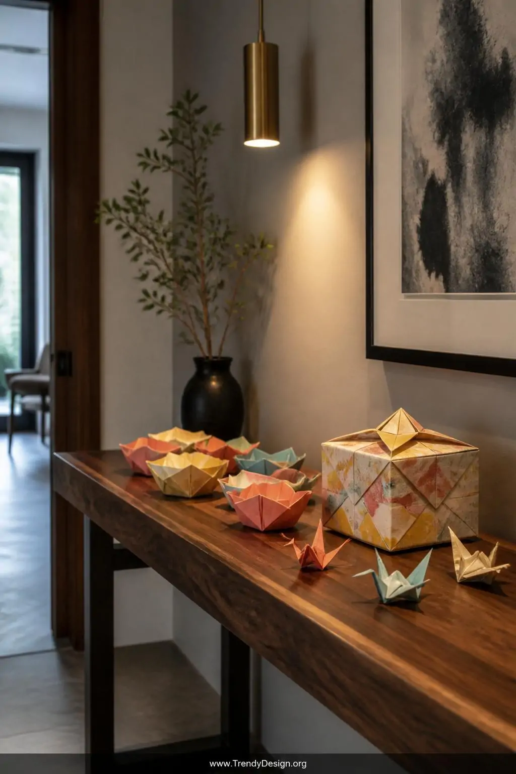 A polished walnut entryway console table holds several small origami bowls and a lidded gift box folded from vibrant calendar