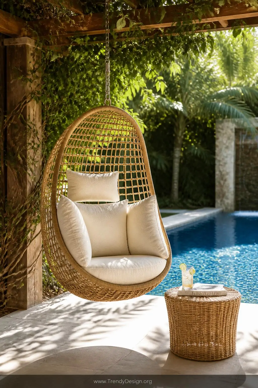 Medium photorealistic shot of a rattan hanging egg chair suspended from a natural wood pergola beside a glittering blue pool,