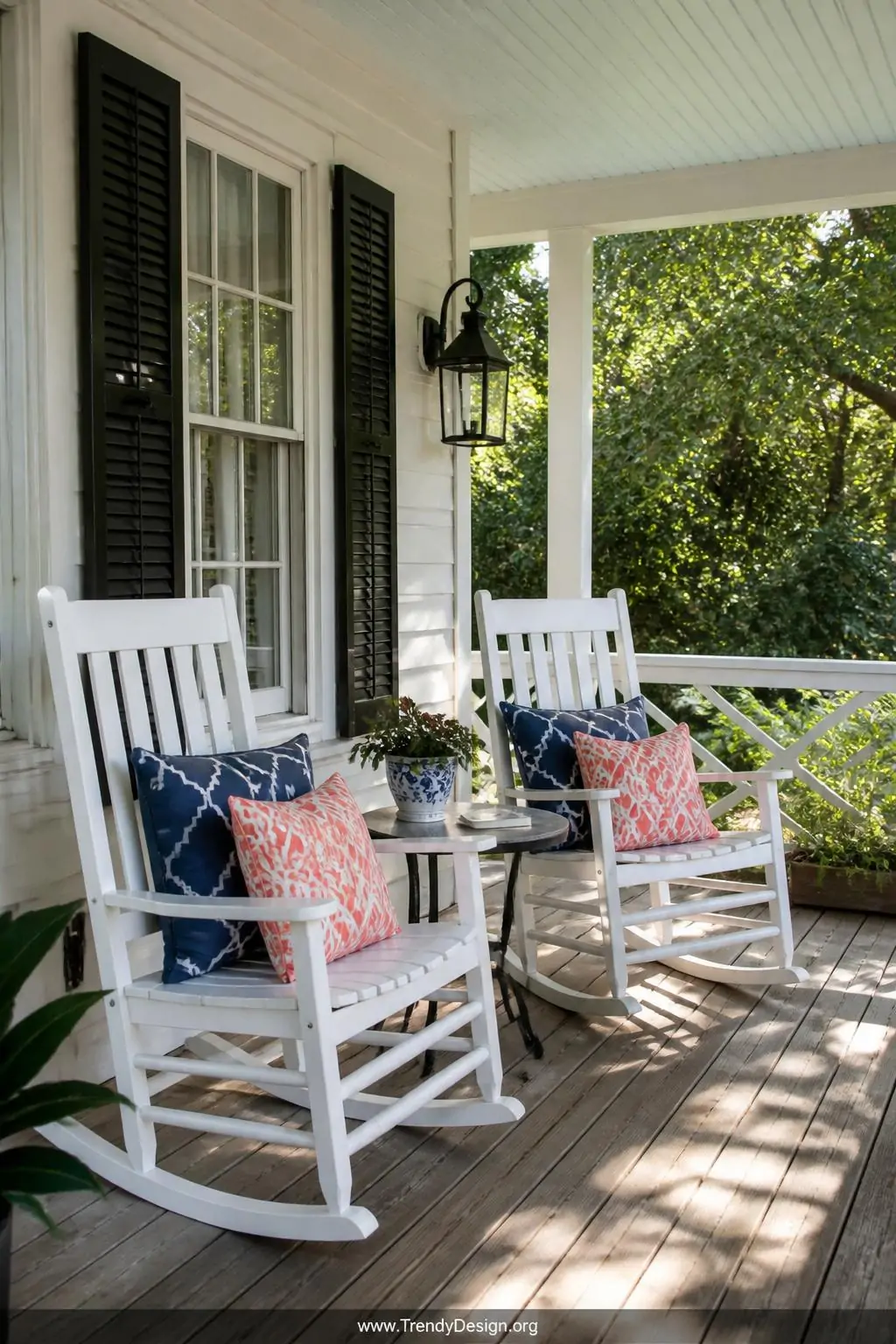Medium shot of a welcoming front porch seating nook with two white rocking chairs positioned beside a small round side table,