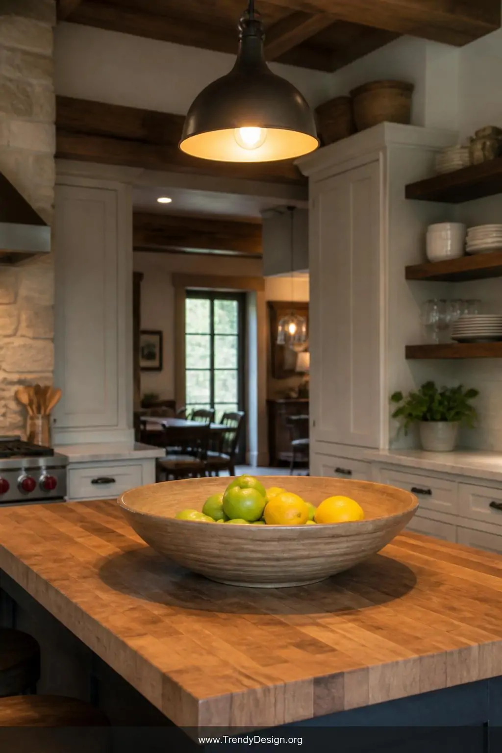 Wide-mouthed shallow clay bowl with smooth blended interior coils holding lemons and green apples on a butcher block kitchen island, warm pendant light overhead, wide shot