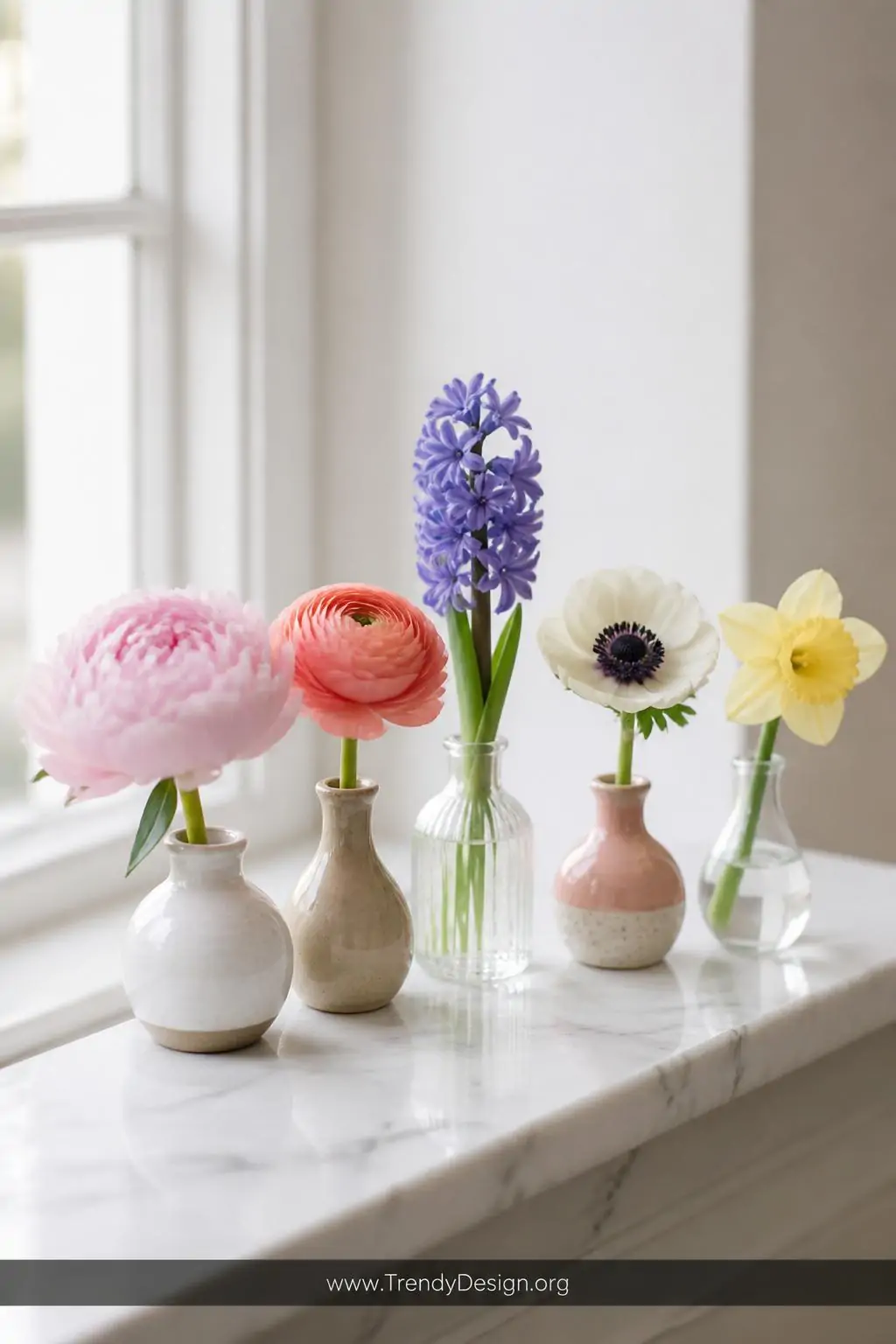 A close-up photorealistic interior shot of a bright white marble windowsill displaying five mismatched small ceramic and glas