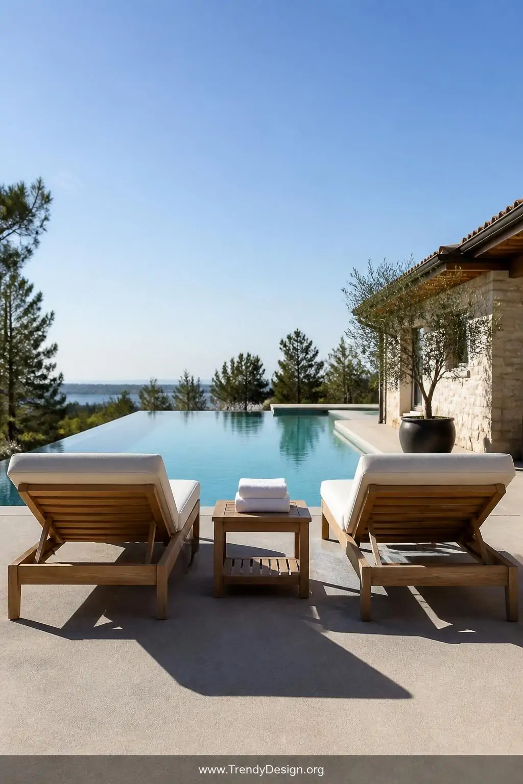 Wide photorealistic shot of two teak chaise loungers positioned symmetrically along a polished concrete pool deck, rich honey