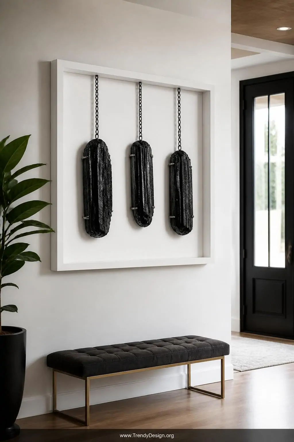 Black tourmaline pendants with striated dark texture mounted inside a white shadowbox frame near a bright entryway wall, bold gallery-worthy contrast of dark gemstones against pale background, medium shot of sleek modern entryway with dramatic focal point lighting.