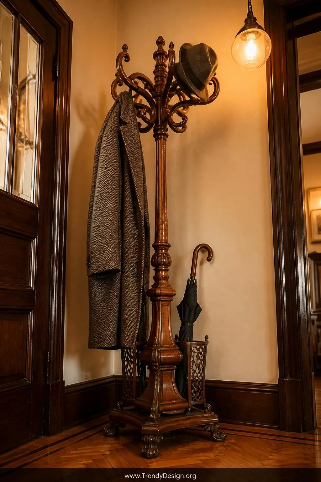 Ornate bentwood Victorian coat stand positioned in the corner of a warm entryway, rich honey-toned curved wooden arms holding a herringbone overcoat and felt hat, cast iron umbrella holders at the base, warm amber pendant light overhead, parquet hardwood floors, closeup shot angled upward to capture the elegant silhouette.