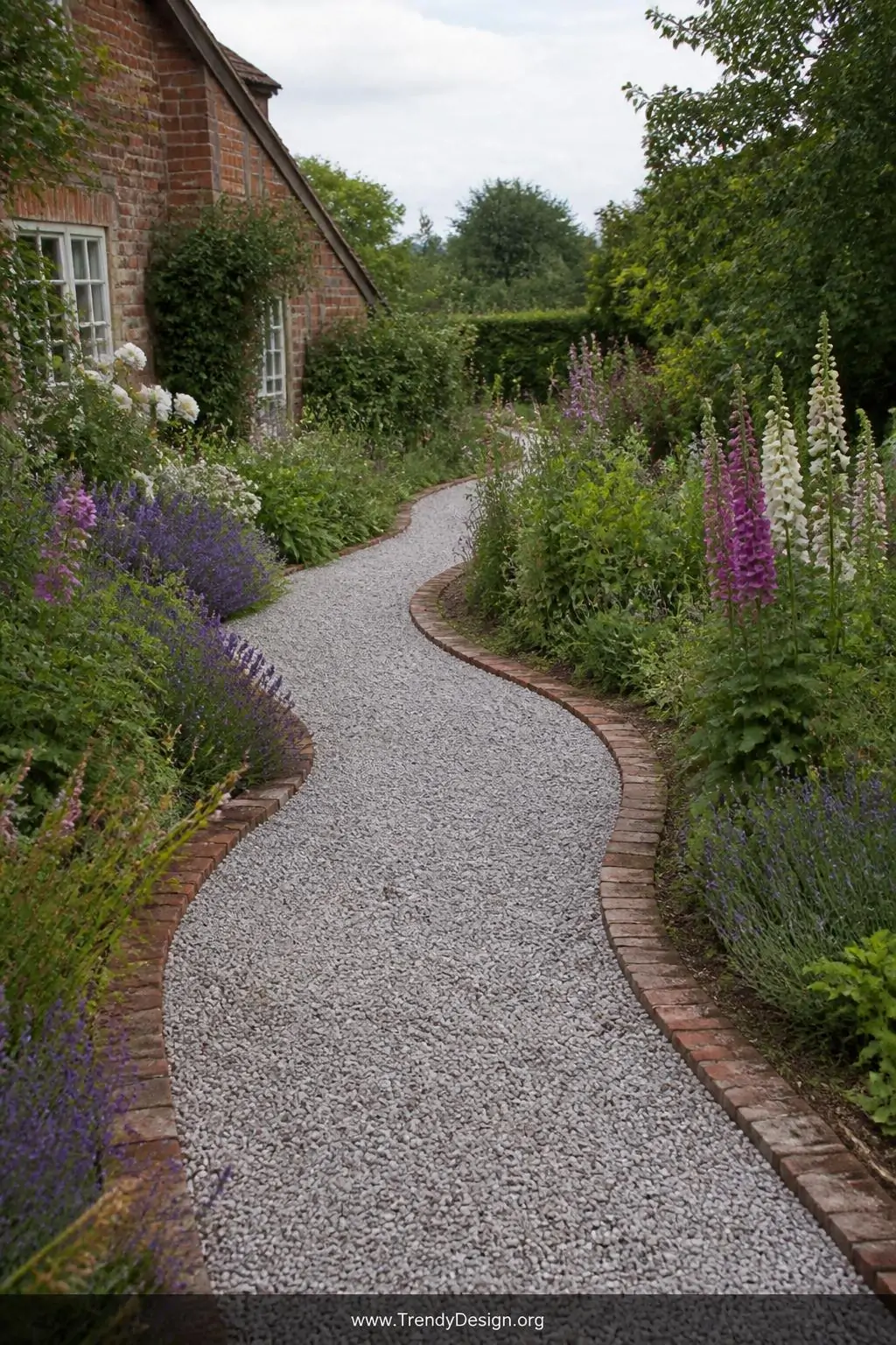 Gravel pathway bordered by reclaimed red-brick edging curving through a lush cottage garden, pale grey pea gravel raked smooth between weathered terracotta bricks, flanked by overgrown lavender and foxgloves, wide shot, soft diffused daylight, photorealistic.