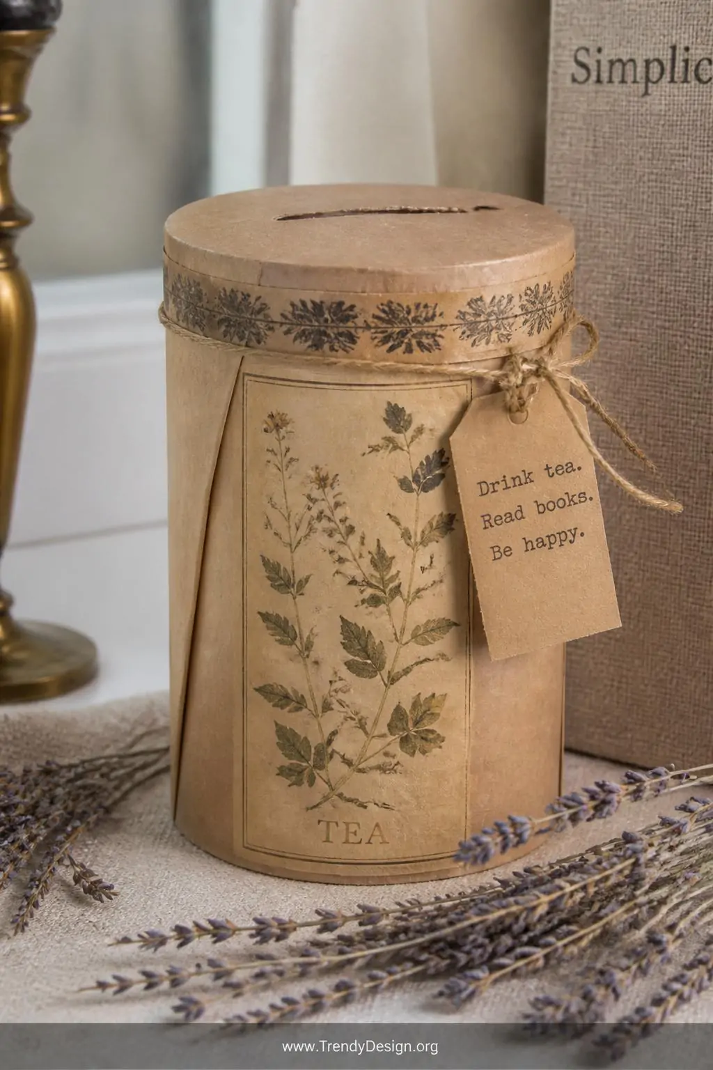 Vintage botanical-print tea tin wrapped in kraft paper with washi tape trim on a linen-covered shelf, small kraft tag with stamped lettering, a thin slot cut into the lid, dried lavender sprigs layered around the base, soft diffused natural daylight, intimate closeup shot showing sustainable texture and aged patina, photorealistic interior design.