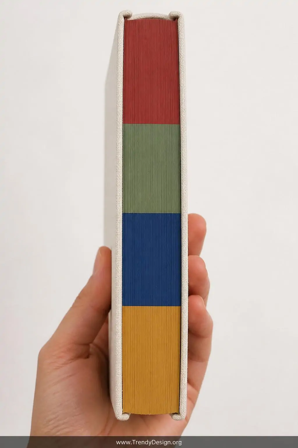 A closeup shot of a closed hardcover notebook held vertically to reveal its painted page edges displaying crisp color-blocked