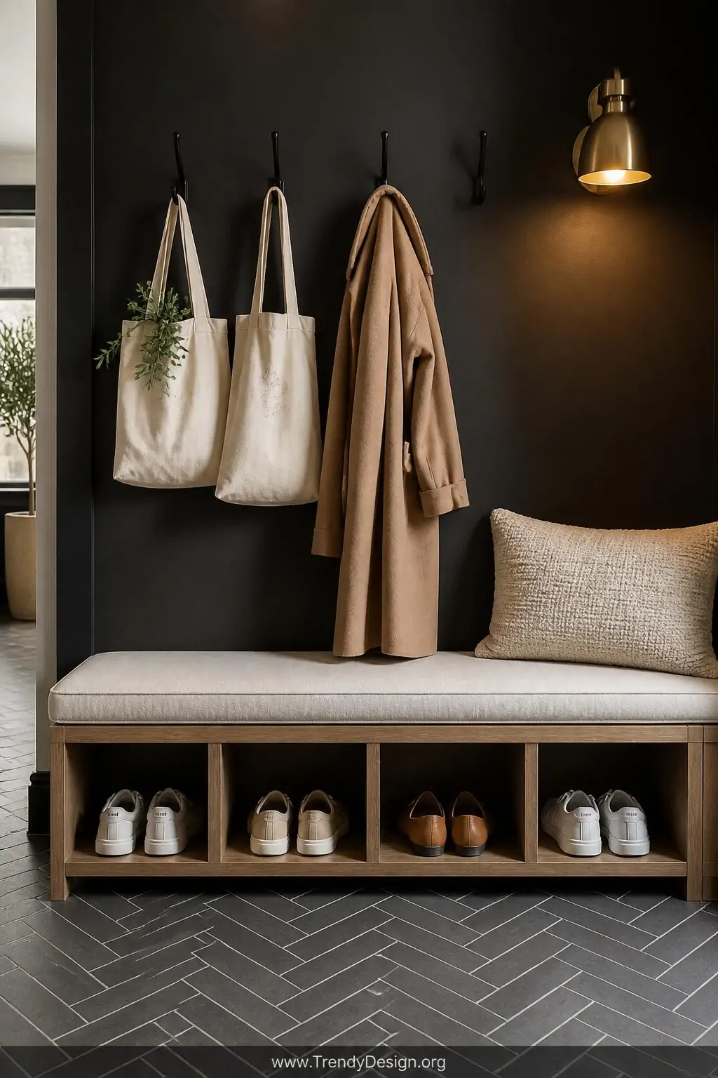 A linen-upholstered entryway storage bench with four open oak-framed cubbies below displays neatly paired sneakers and flats 