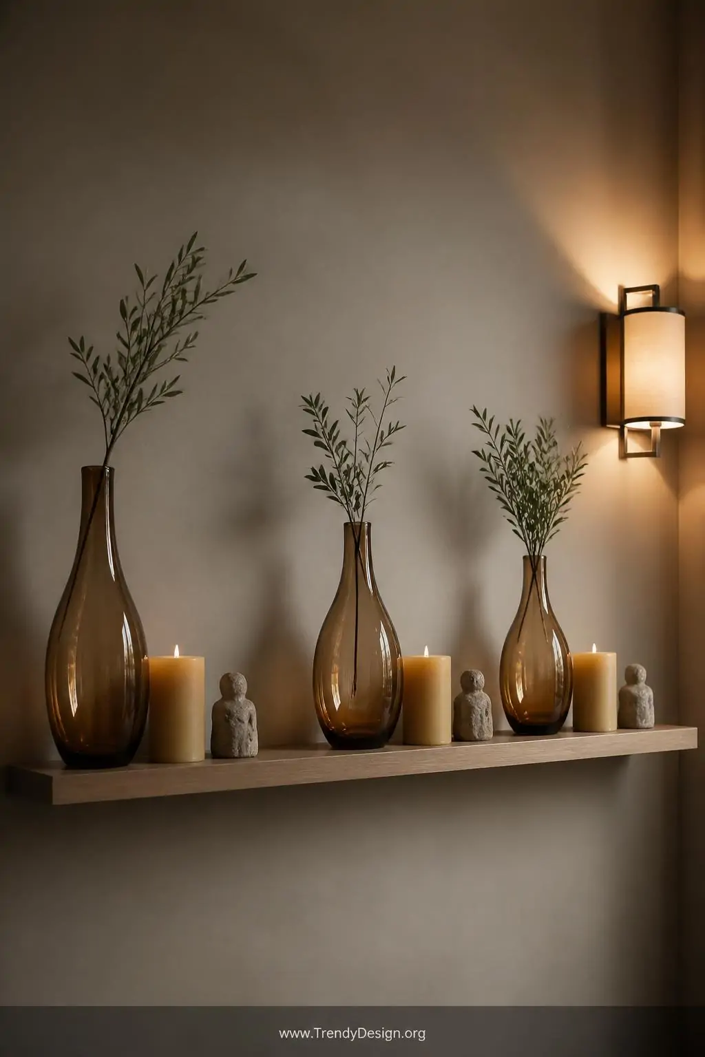 Medium shot of an open floating shelf against a warm greige wall displaying three precisely composed groupings each following