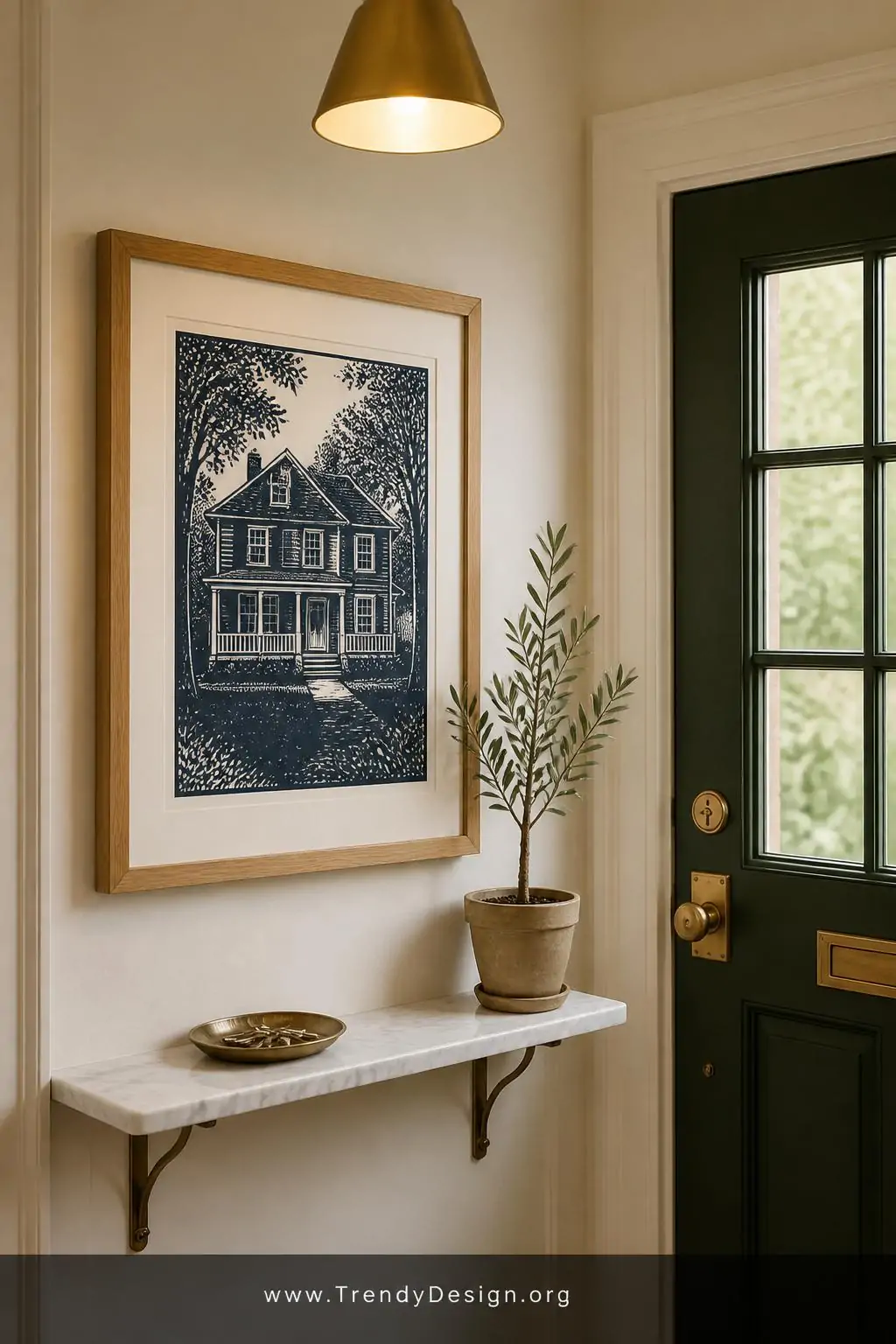 A medium interior shot of a charming entryway where a single deep navy linocut house portrait print in a wide natural oak fra