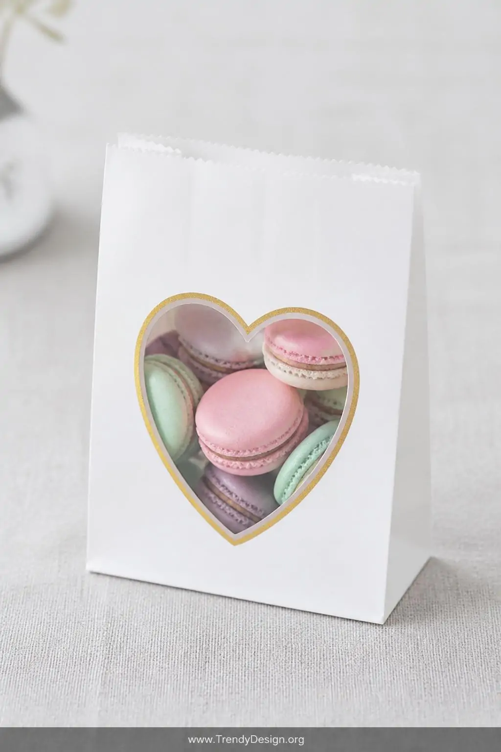 A medium-shot of a white paper bag with a heart-shaped cellophane window cut into the front, revealing a neat arrangement of 
