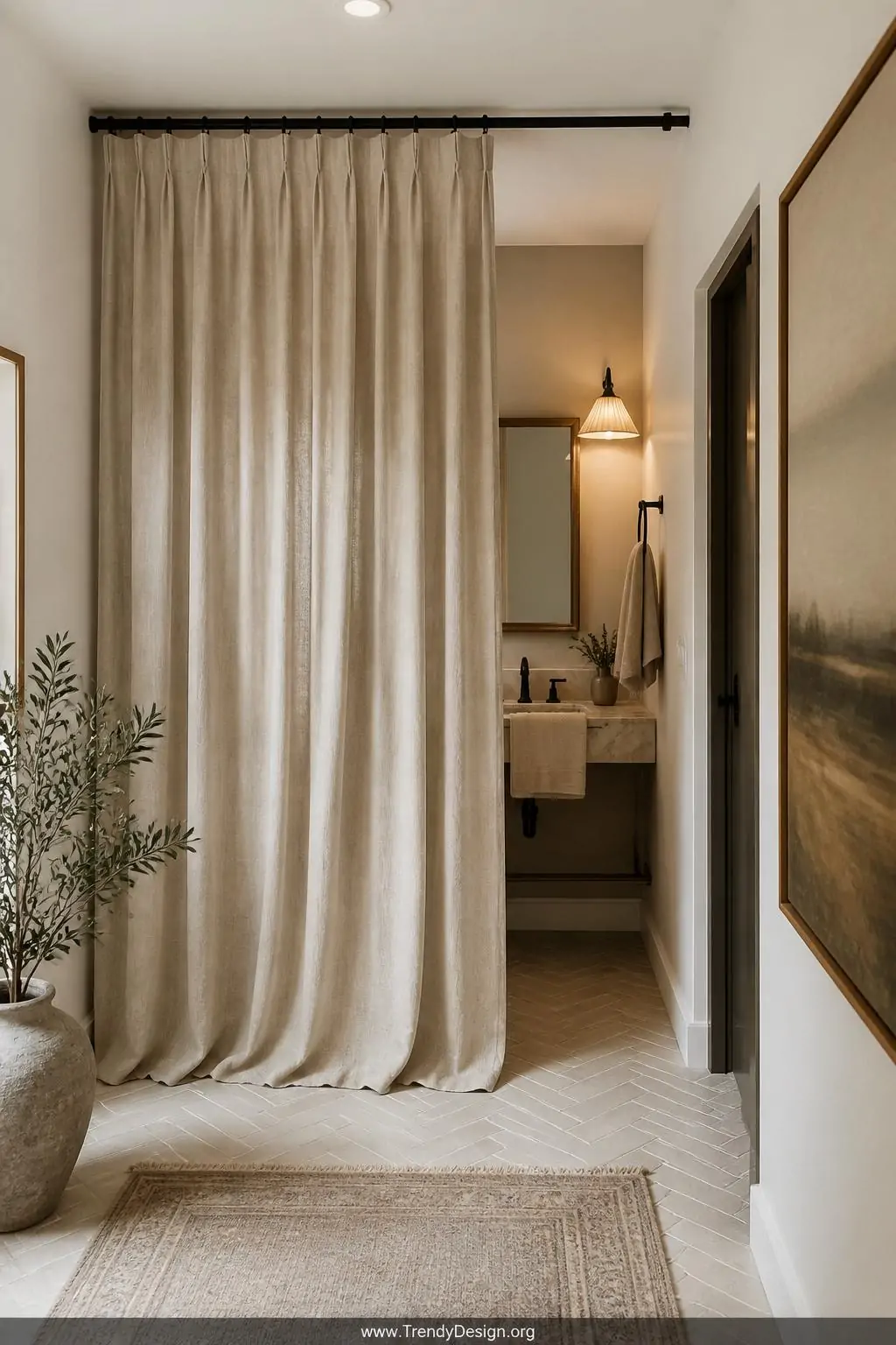 Heavyweight natural linen curtain panel hanging from a ceiling-mounted matte black rod as a powder room entrance, wide shot, soft ivory and warm taupe tones, fabric pooling slightly at herringbone tile floor, warm ambient lighting casting gentle shadow folds, coordinating linen hand towels visible inside, photorealistic interior design.