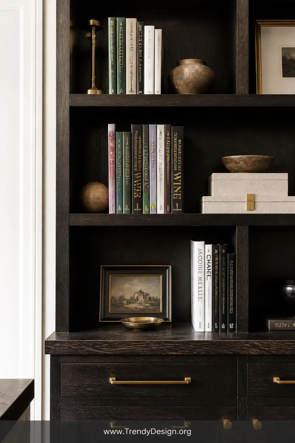 Ebony stained wooden bookshelf styled with brass hardware and white walls in a dramatic home office, editorial style, deep near-black finish making colorful book spines and natural linen accents pop like gallery objects, closeup shot capturing the rich dark wood grain still visible beneath the bold stain in sharp directional lighting.