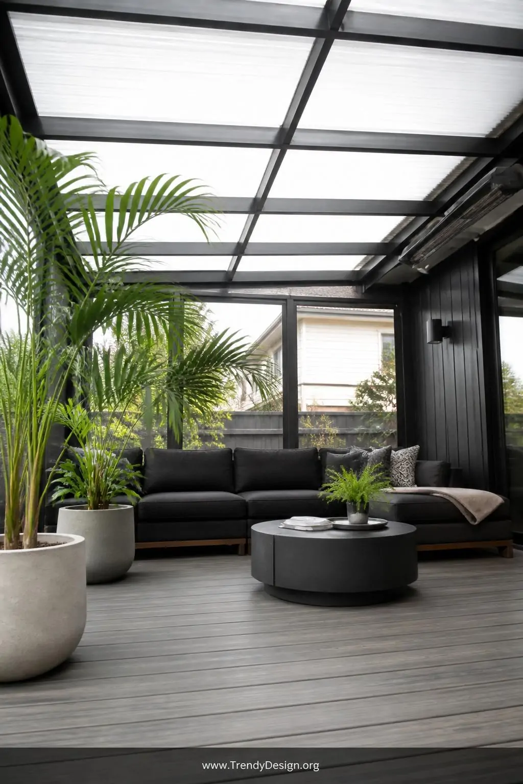 Closeup of a polycarbonate translucent roof panel installed over a furnished outdoor room, diffused cool natural light pouring through the milky surface onto a smooth composite deck with deep charcoal sectional sofa and potted tropical palms in matte concrete planters, photorealistic interior design.