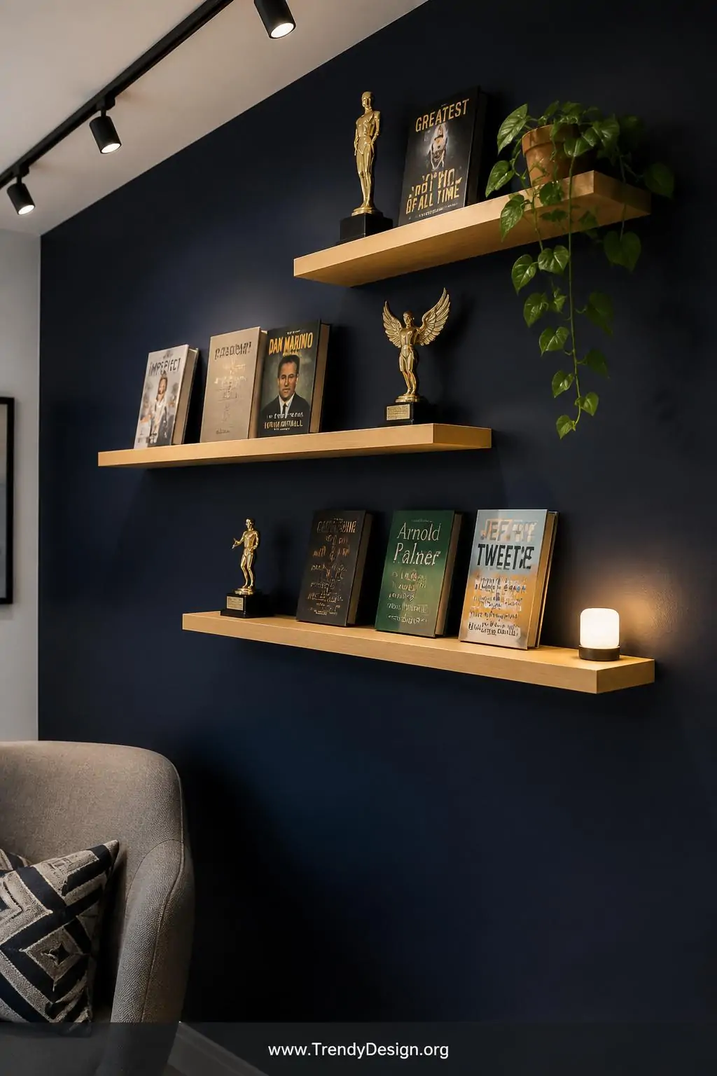 A cluster of white oak floating shelves mounted high on a deep navy blue accent wall displays trophy figures, hardback books 