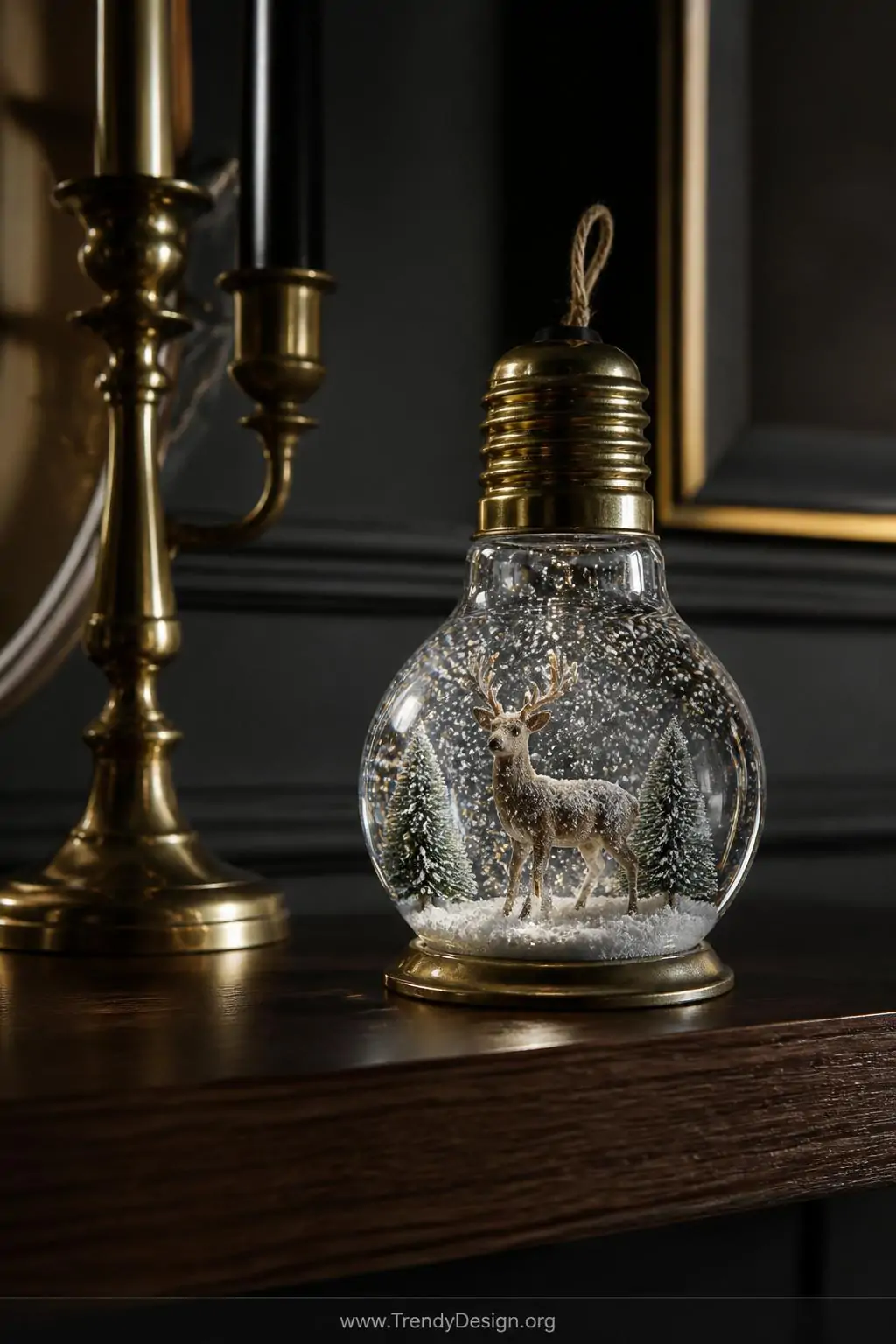Miniature snow globe inside a rounded glass light bulb showing a tiny frosted woodland deer figurine swirling with white glitter snowflakes, resting on a dark walnut shelf beside vintage brass candlesticks, dramatic moody interior lighting, closeup shot.