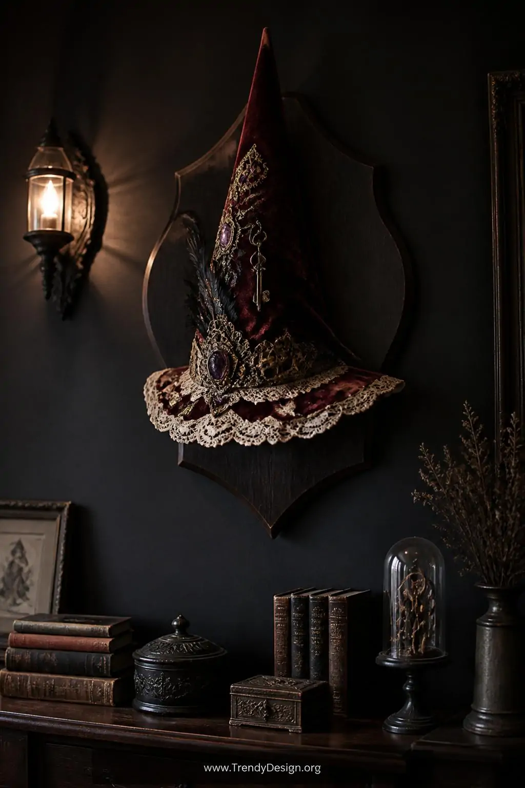 A tall pointed hat constructed from deep burgundy velvet trimmed with antique ivory lace along the brim is mounted on a dark 