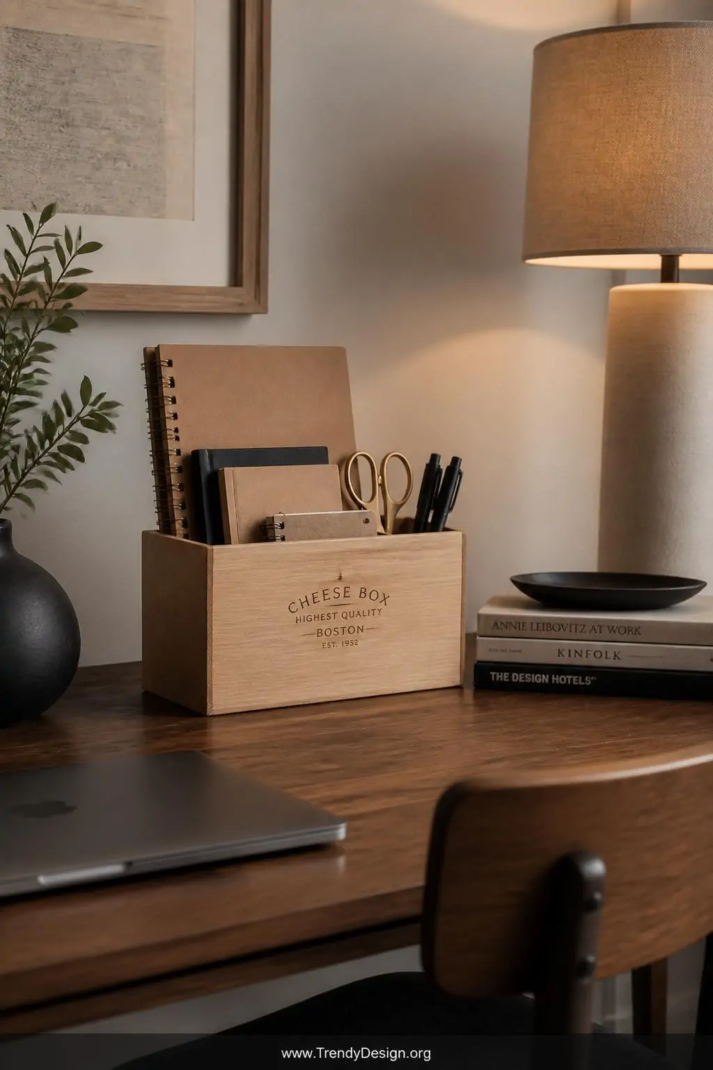 Upright natural wood cheese box desk organizer holding kraft notebooks, brass scissors, and matte black pens on a walnut home office desk beside a linen lamp casting warm directional light, Scandinavian minimalist style, wide shot
