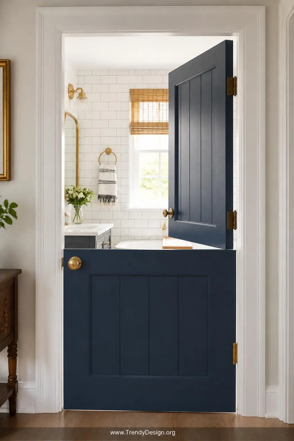 Painted navy blue Dutch door split horizontally open at a bright family bathroom entrance, medium shot, top half open revealing white subway tile walls inside, aged brass hardware on both halves, warm natural light streaming through, crisp white door frame contrast, cheerful and charming atmosphere, photorealistic interior design.