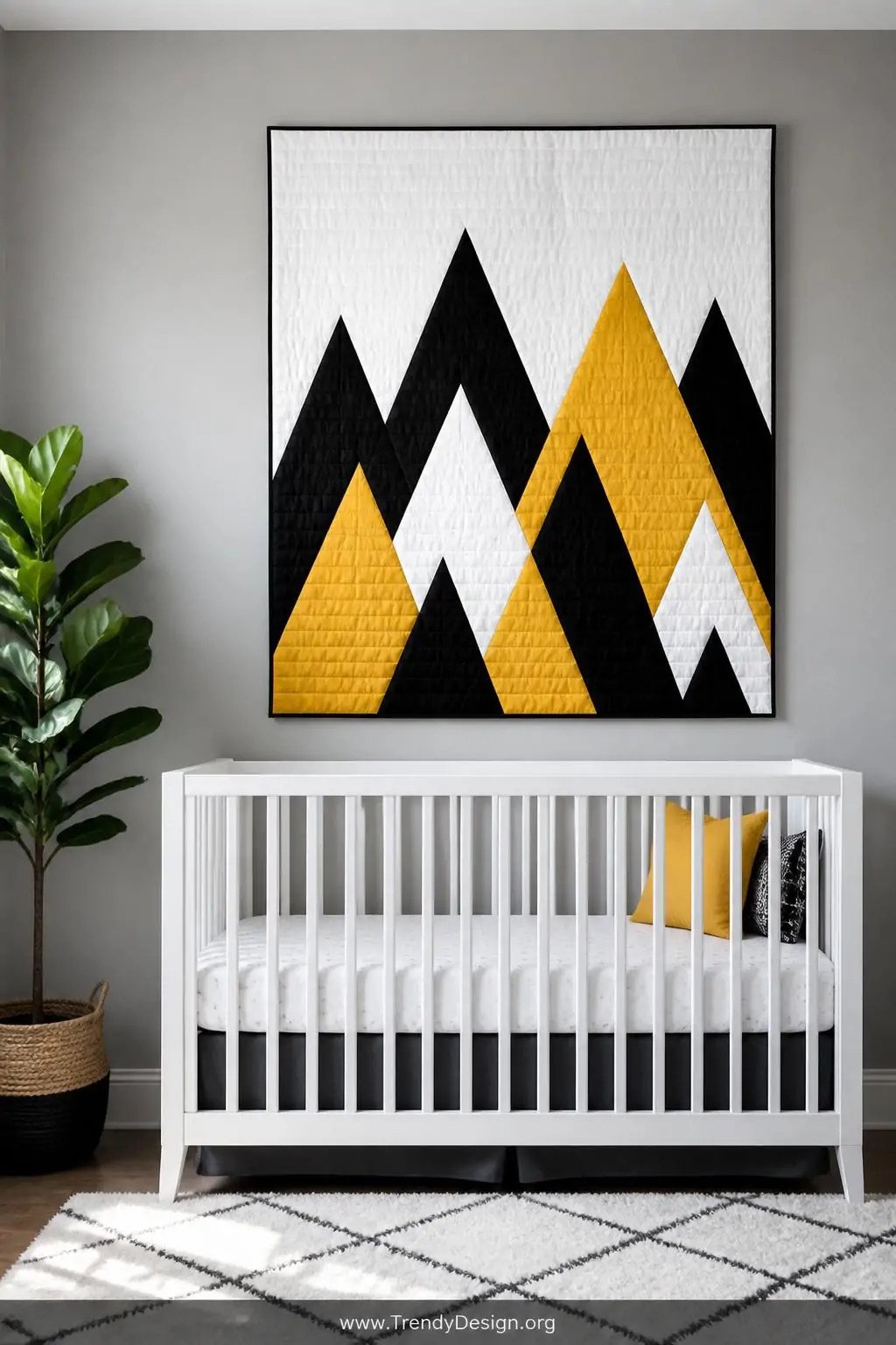 Modern geometric triangle baby quilt mounted as wall art above a sleek matte white crib, cool minimalist nursery lighting, wide shot showing bold mountain peak triangle arrangement in black, white, and mustard yellow against a smooth light grey painted wall with a single potted fiddle leaf fig in the corner.