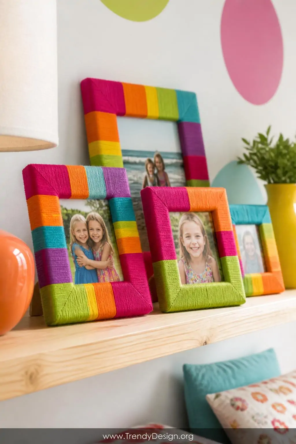 Vibrant embroidery floss-wrapped picture frames clustered on a pale wood floating shelf, colorful children's bedroom, chunky rainbow stripe and color-block wrapped wooden frames in magenta, tangerine, and lime displaying cheerful photos, soft overhead light, closeup.