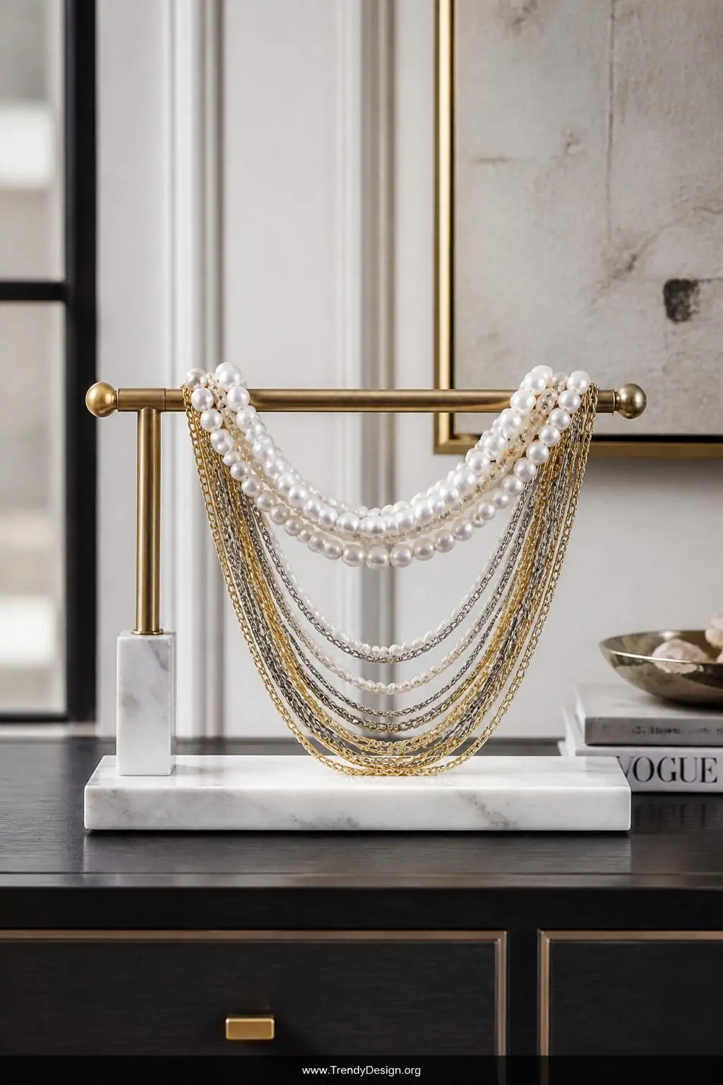 Freshwater baroque pearls threaded above cascading mixed gold and silver chain tassels draped elegantly across a marble and brass jewelry stand on a sleek modern dresser, cool diffused studio light emphasizing organic pearl texture against metallic chain, medium shot.