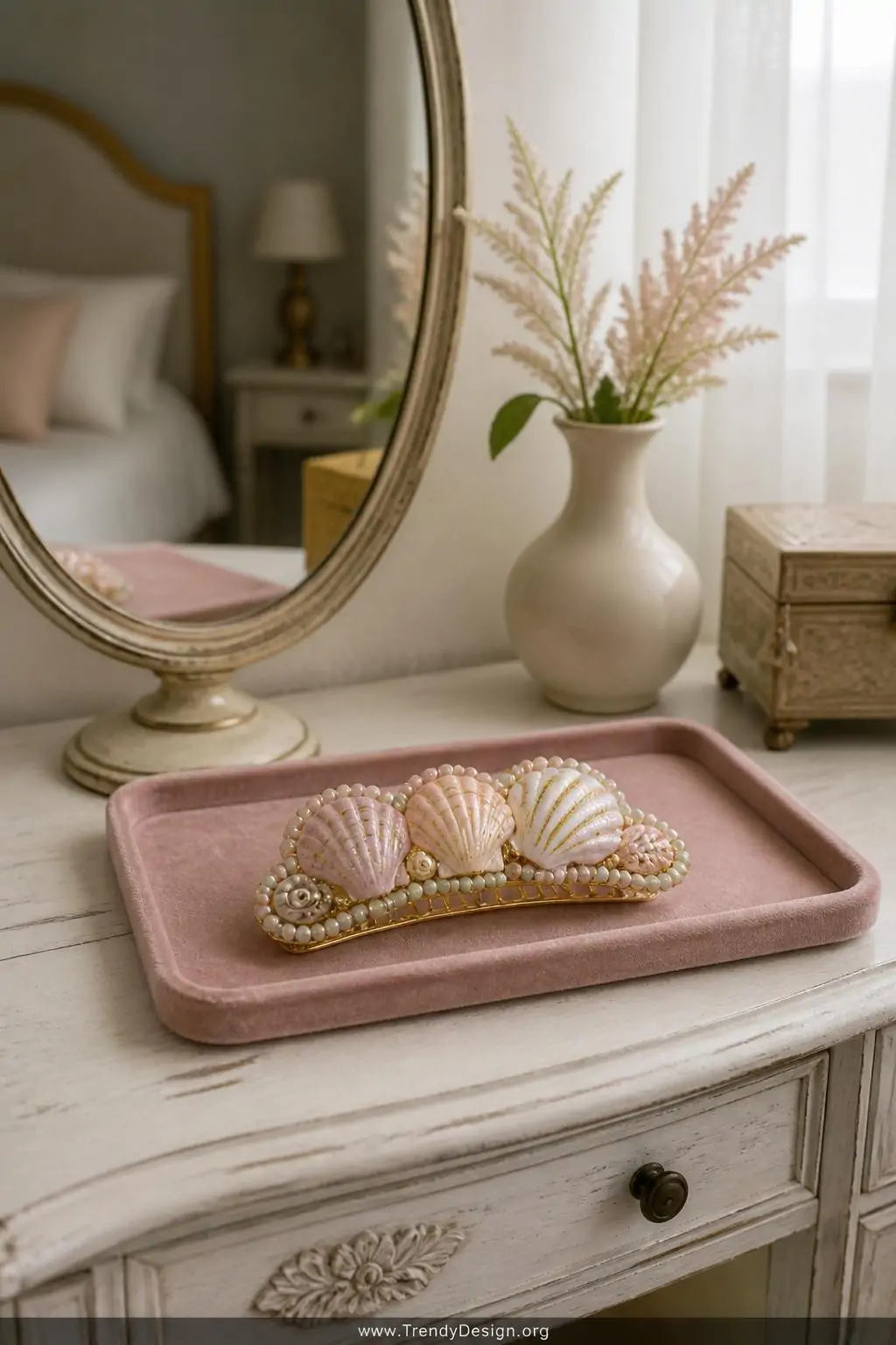 Clam shell hair barrette with pastel gold-leaf painted shells and seed bead detailing displayed flat on a soft blush velvet tray beside a small mirror on a whitewashed bedroom dresser, soft diffused natural window light, medium shot, photorealistic interior design