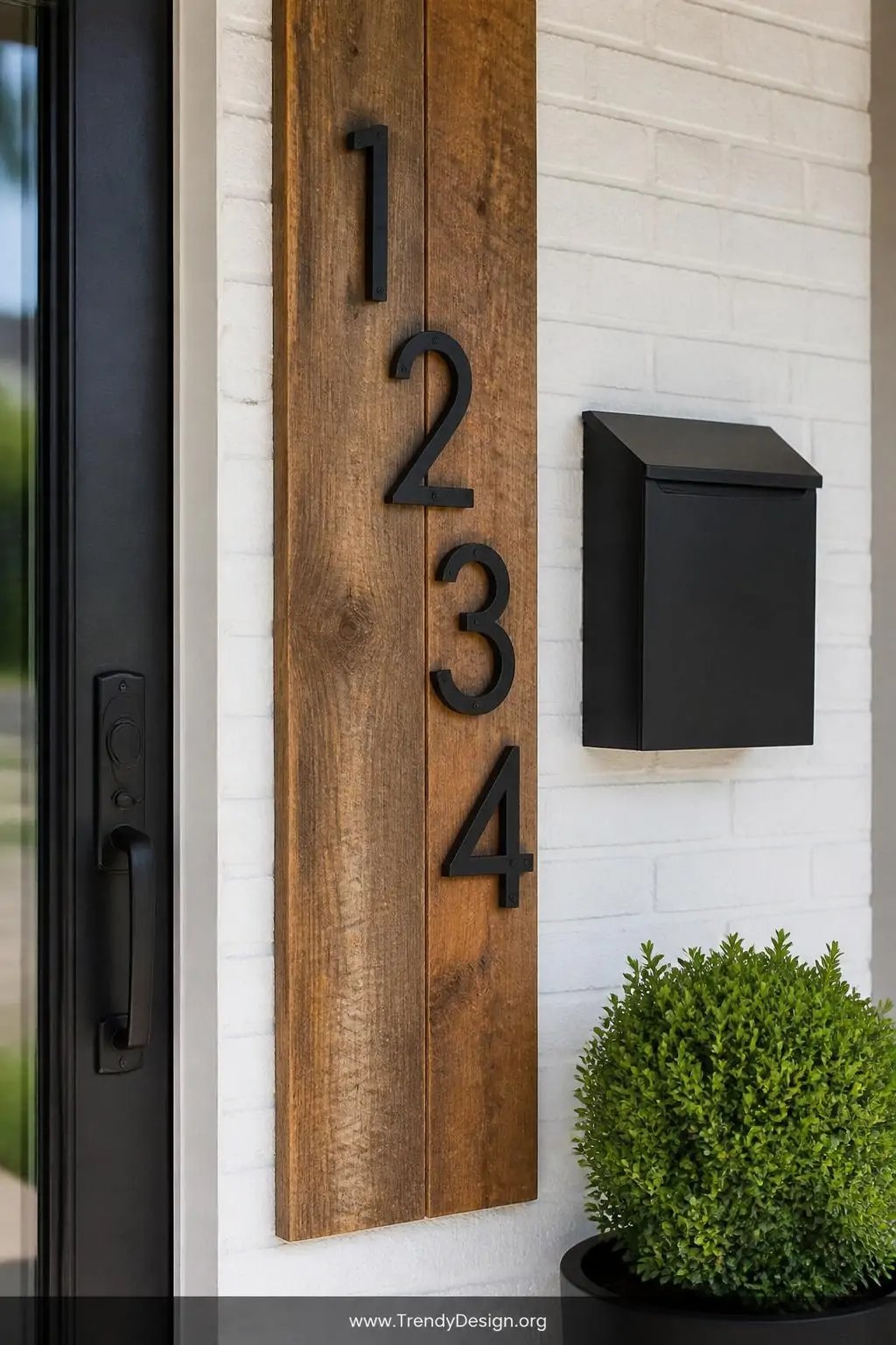 Closeup shot of a beautifully styled front door entry detail featuring staggered matte black house numbers mounted on a recla