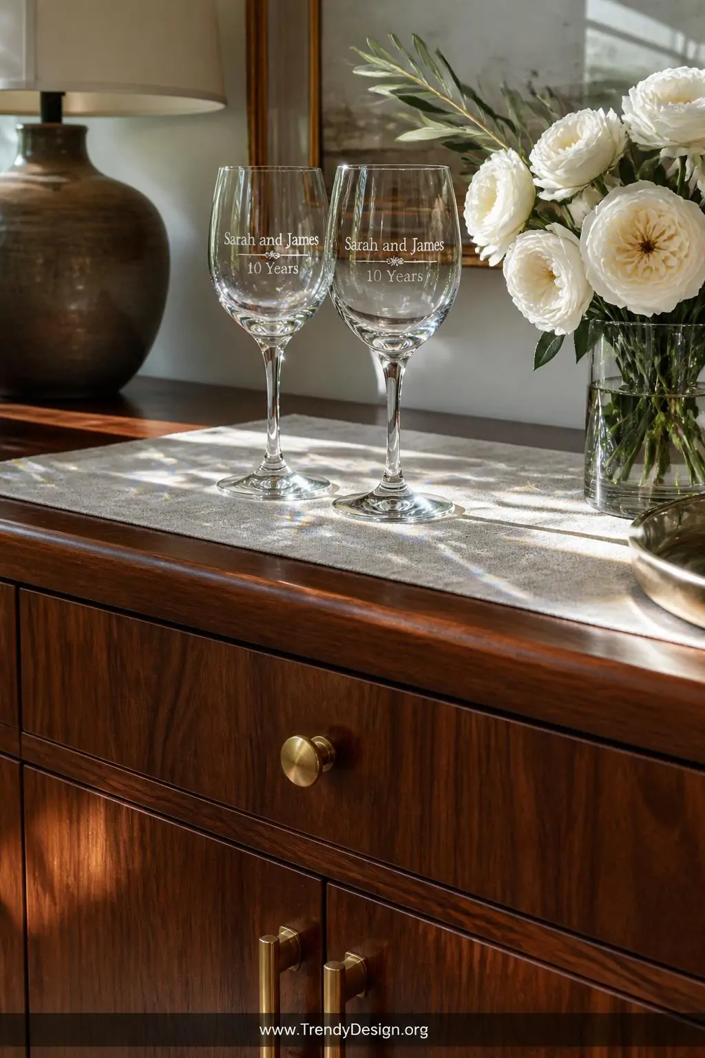 A closeup, photorealistic shot of a sunlit dining room sideboard in rich walnut with brushed brass hardware, where two crysta