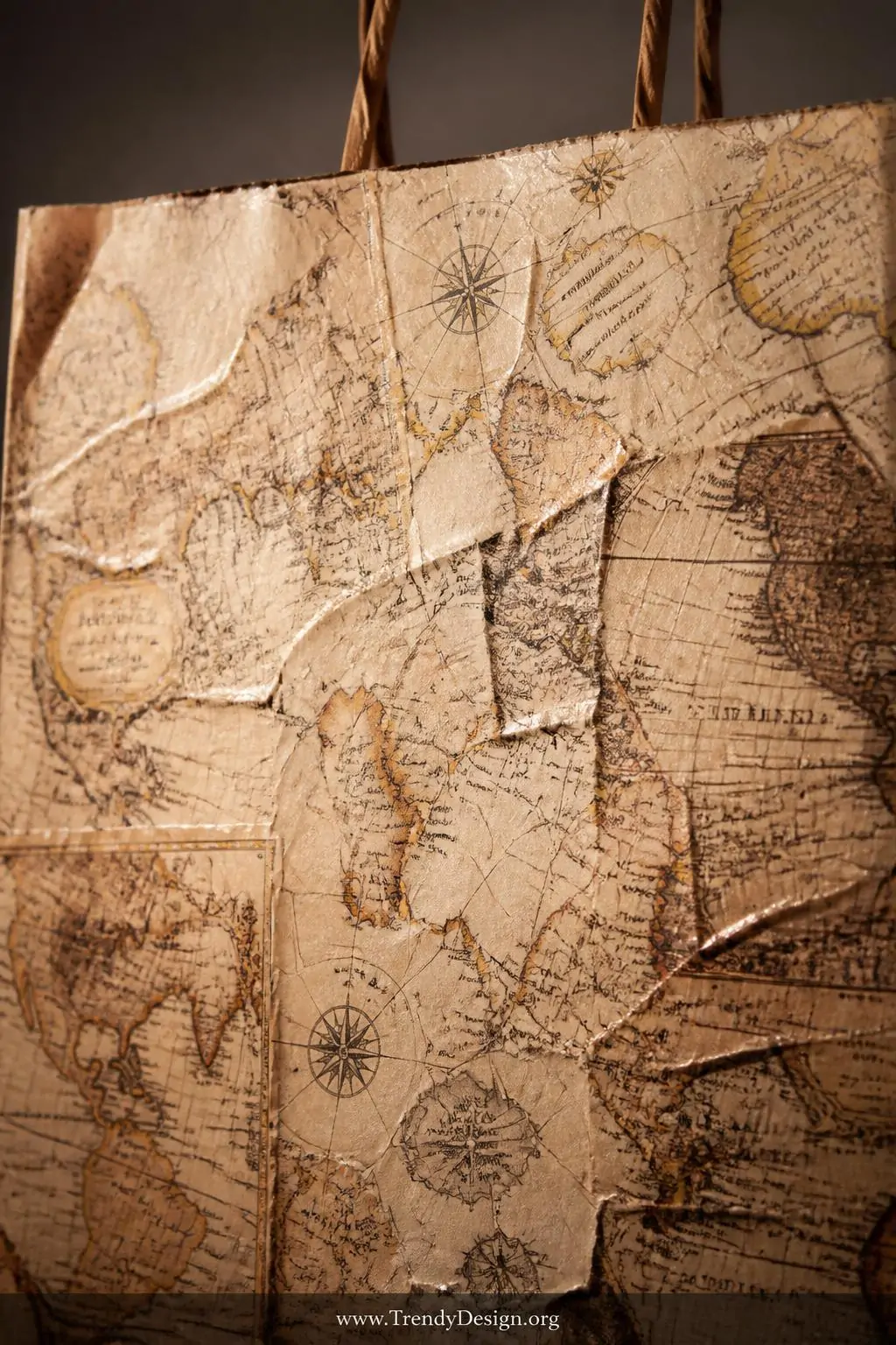A close-up shot of a single paper bag surface completely covered in torn vintage map pages adhered with glossy Mod Podge, the