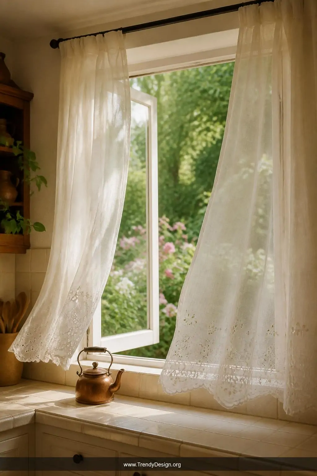 Delicate ivory voile curtains with embroidered eyelet edges floating at an open casement kitchen window framing a lush garden view, medium shot, soft diffused light washing across cream ceramic tiles and a vintage copper kettle on the sill, photorealistic interior design.