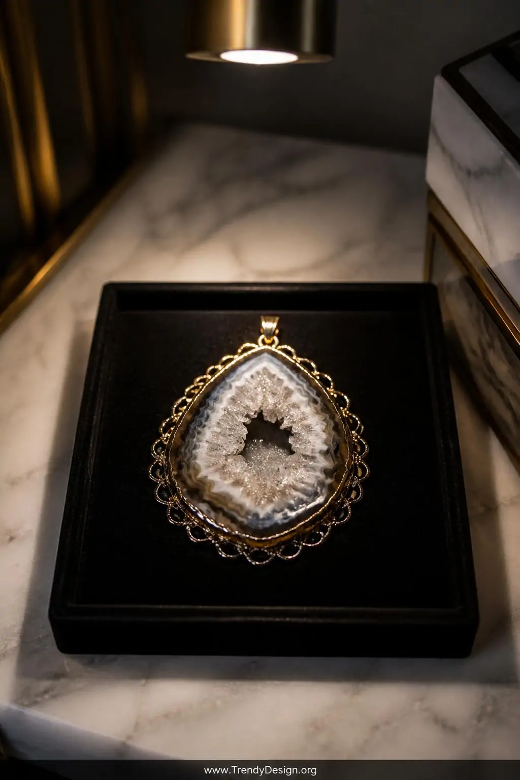 Druzy agate slice pendant framed in gold-filled scalloped wire loops displayed on a black velvet jewelry tray atop a marble nightstand, a single overhead spotlight catching the glittering crystal formations, closeup revealing the sparkling druzy center