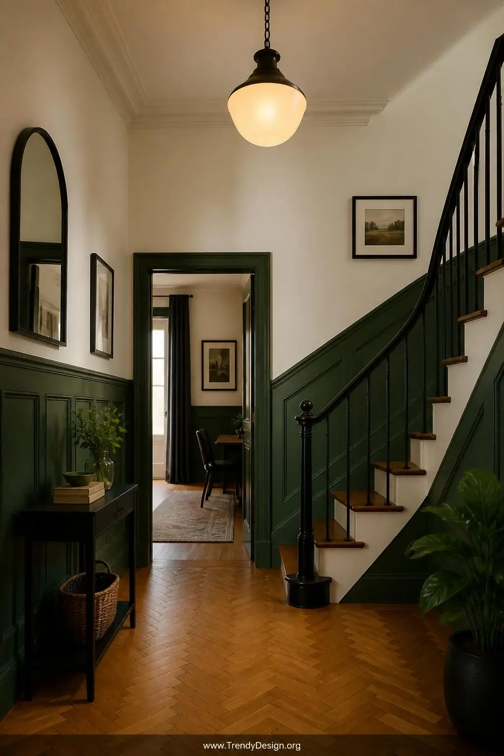 Medium shot of an elegant entryway staircase hall with wainscoting panels painted hunter green below the chair rail and warm 
