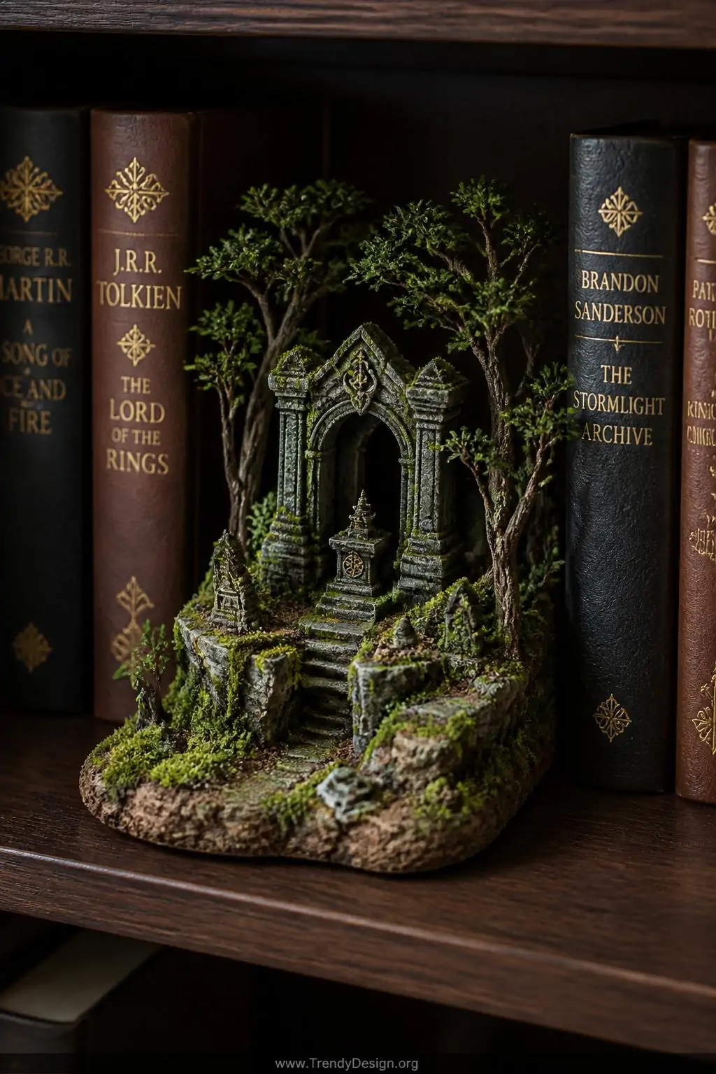 Miniature forest shrine terrain piece with mossy gray foam stonework altar, rich emerald flock groundcover, tiny twig trees, and earthy brown textured soil displayed on a dark wood bookshelf between leather-bound fantasy novels, soft natural light, closeup