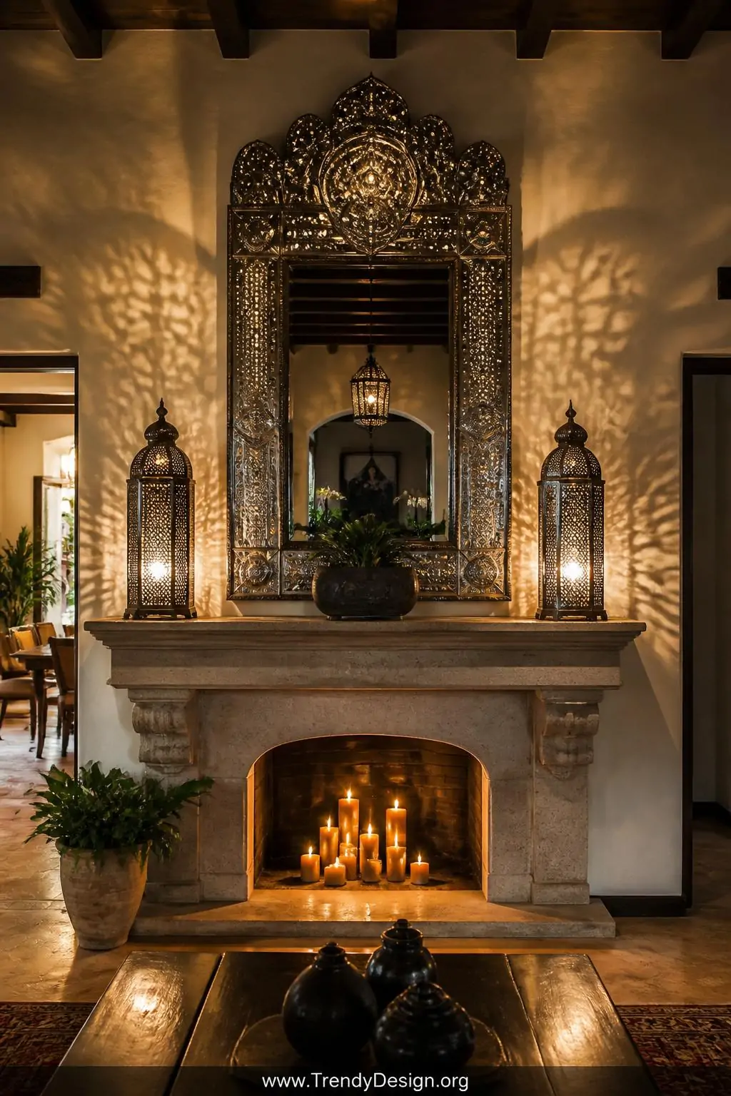 Large ornate punched tin hojalata mirror mounted above a stone fireplace mantel, candlelight from flanking tin lanterns casting intricate dappled patterns across white plaster walls, warm amber glow filling a dramatic entryway, wide shot of a colonial-style Mexican interior.