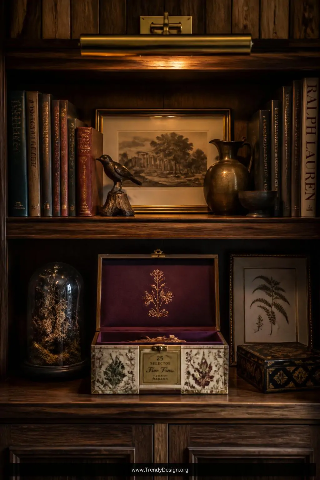 Upcycled cigar box with aromatic hinged wood lid painted deep plum inside and decoupaged with vintage botanical illustrations on a dark walnut curiosity shelf, rich jewel-toned interior glowing under a warm brass picture light above, wide shot revealing surrounding antique objects and moody sophisticated atmosphere, photorealistic interior design.