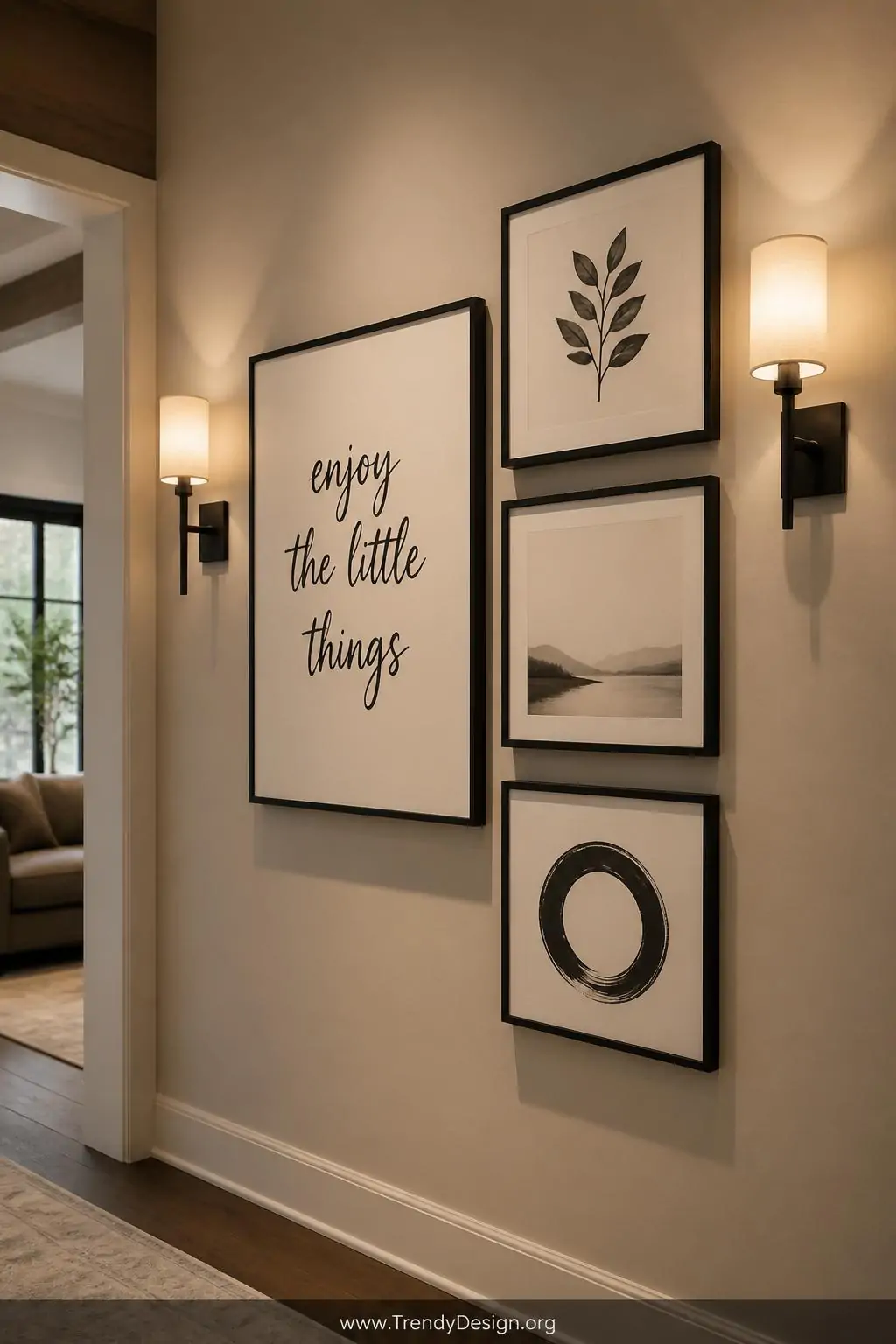 Black brush-lettered quote in a slim black frame grouped in a gallery wall arrangement with three matching frames on a warm greige hallway wall, soft sconce lighting casting gentle shadows on heavy cream cardstock, medium shot