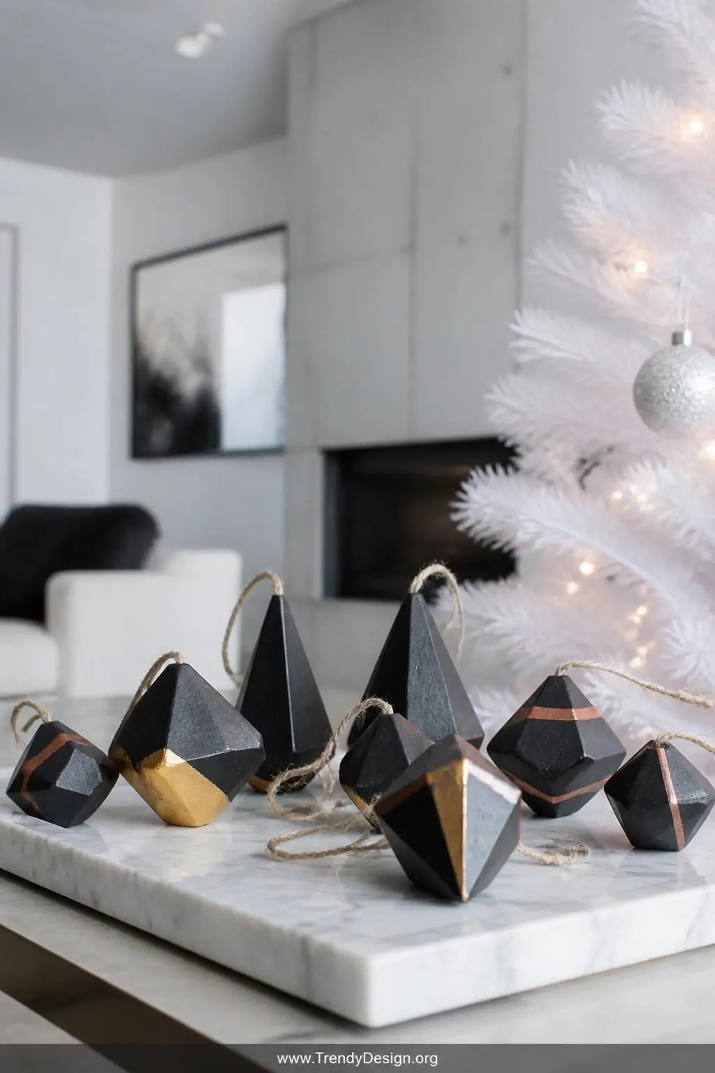 Collection of geometric salt dough ornaments in black with gold-dipped tips and copper stripe details arranged on a sleek marble tray beside a white minimalist Christmas tree, cool daylight, wide shot